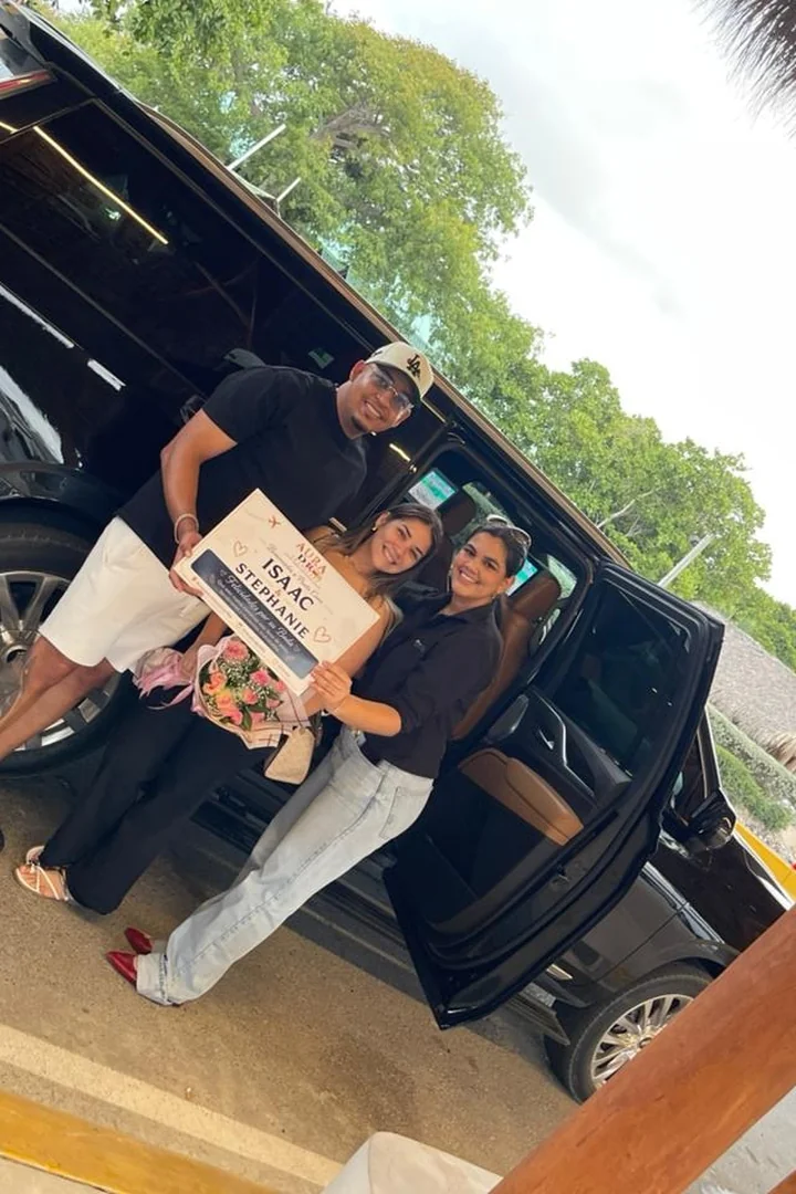Representante de Aura DR Transfers dando la bienvenida a clientes con cartel personalizado para su traslado en el Aeropuerto Internacional de Punta Cana.