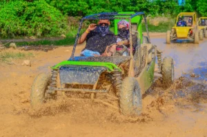Primer plano de pareja en Buggy verde cruzando camino de lodo seguido de otros buggies amarillos