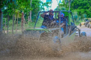 Pareja en buggy a alta velocidad levantando gran cantidad de lodo, disfrutando su aventura en buggy