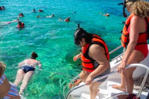 Turistas descendiendo escaleras de catamarán para practicar snorkel en tour Party Boat Punta Cana